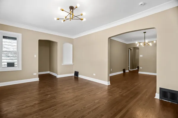 a view of an empty room with window and wooden floor