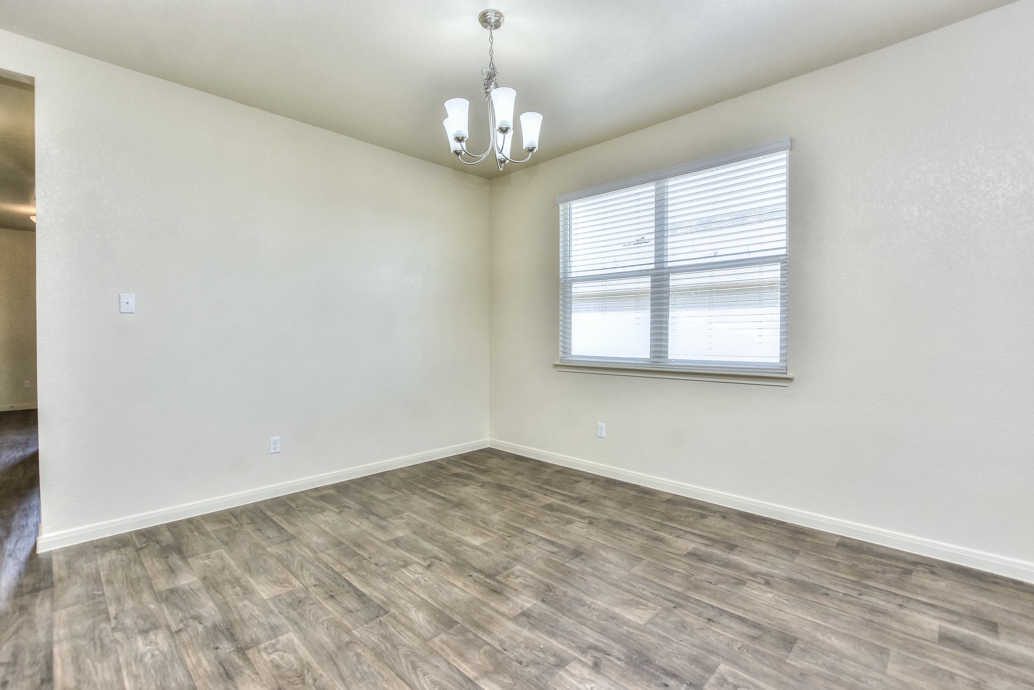 6201 Kildare Drive Georgetown, TX 78626 - Photo 14 of 29 Unfurnished room featuring baseboards, wood finished floors, and a notable chandelier