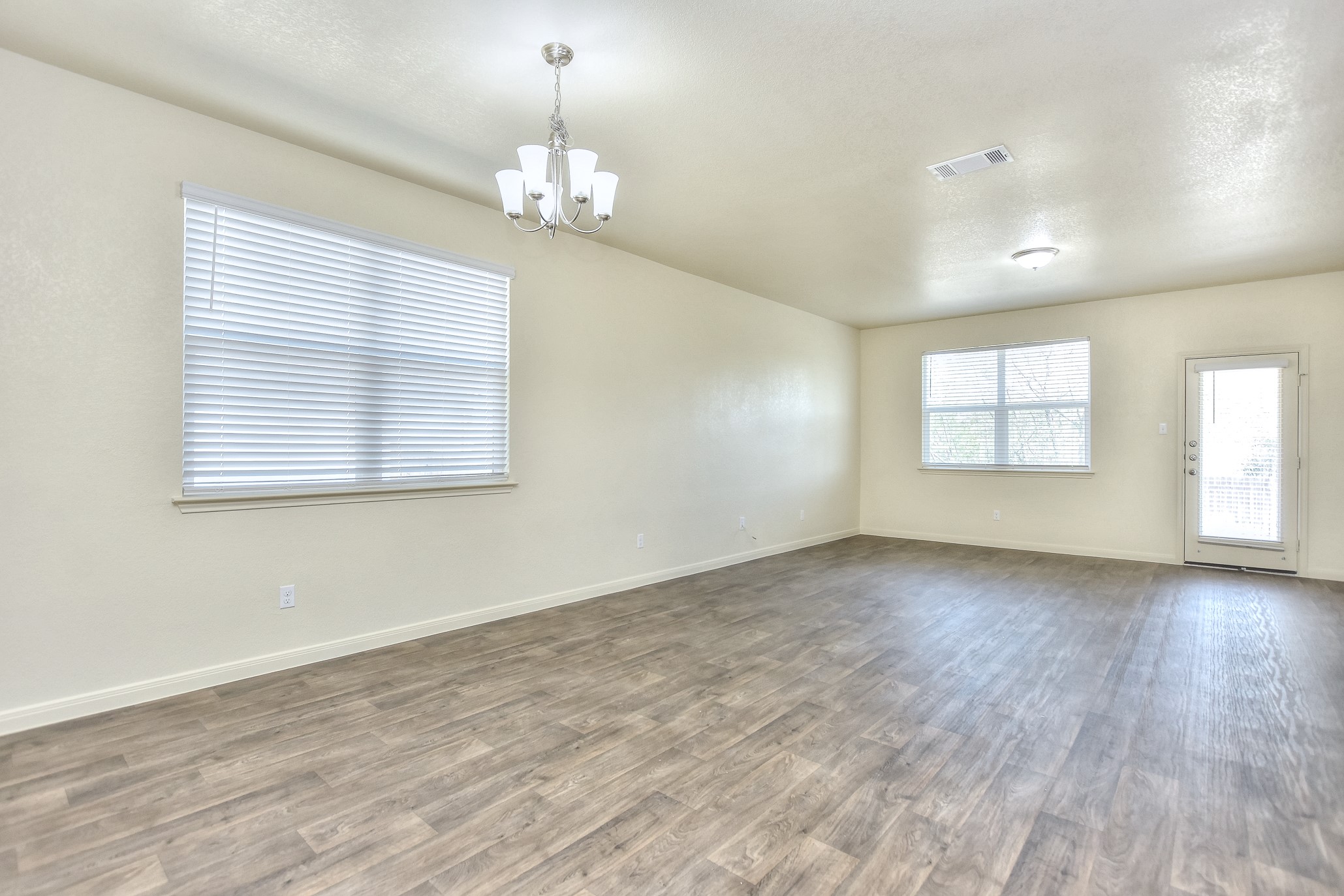 6201 Kildare Drive Georgetown, TX 78626 - Photo 15 of 29 Spare room with baseboards, visible vents, an inviting chandelier, and wood finished floors