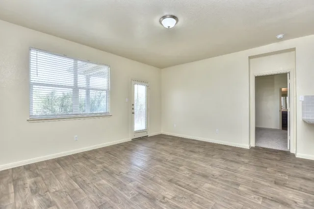 an empty room with wooden floor and windows