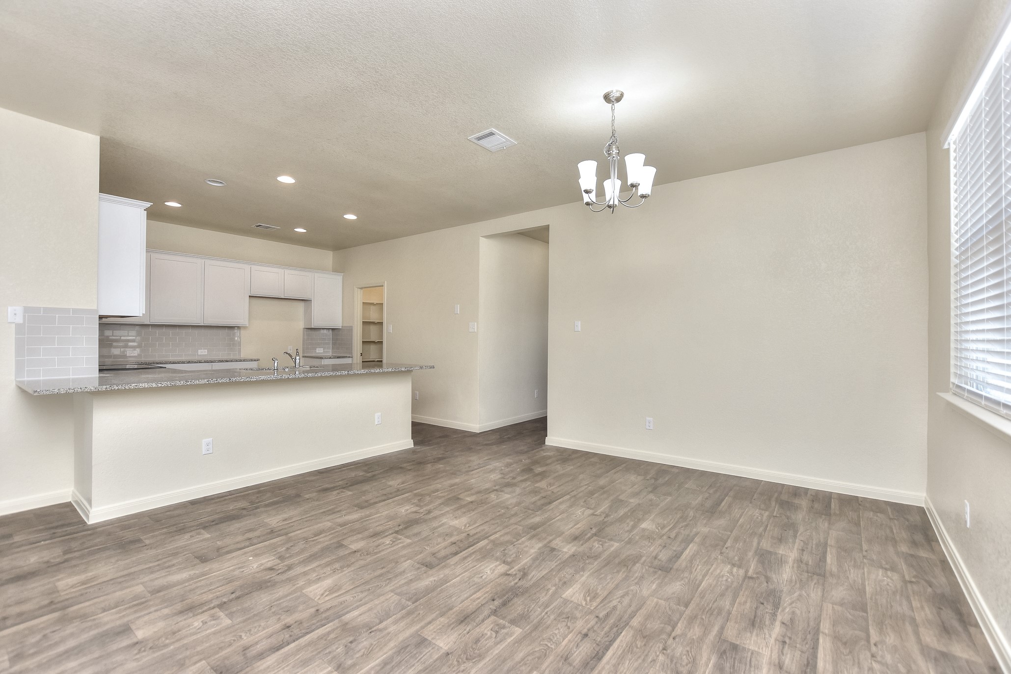 6201 Kildare Drive Georgetown, TX 78626 - Photo 18 of 29 Kitchen with backsplash, white cabinetry, wood finished floors, visible vents, and an inviting chandelier