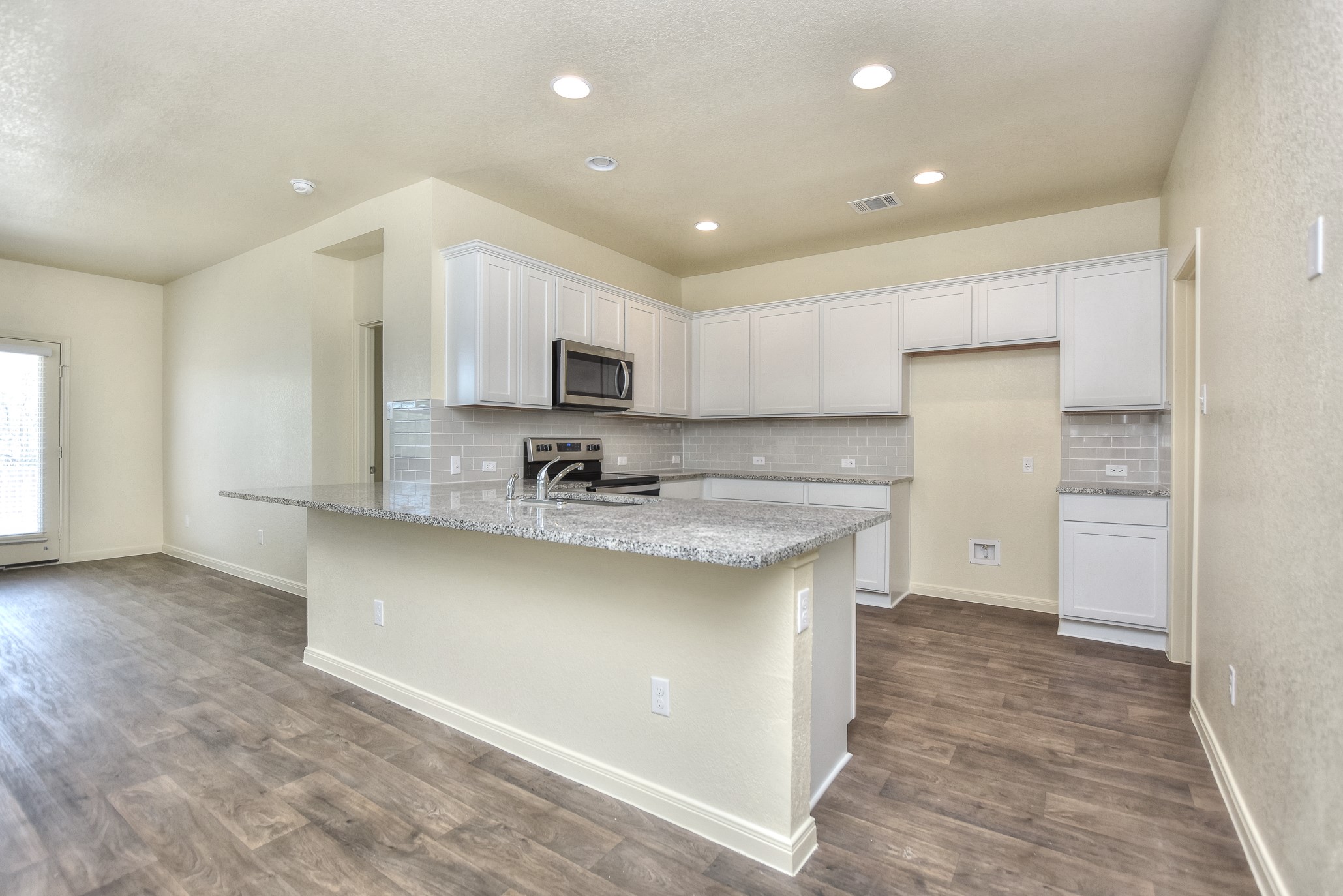 6201 Kildare Drive Georgetown, TX 78626 - Photo 19 of 29 Kitchen with appliances with stainless steel finishes, a peninsula, visible vents, white cabinets, and dark wood-type flooring