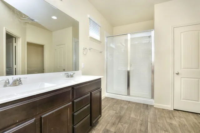 a bathroom with a double vanity sink mirror and shower