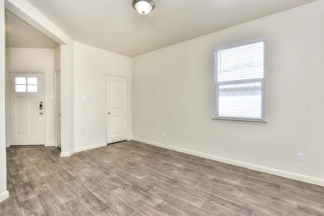 a view of an empty room with wooden floor and a window