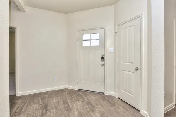 a view of an empty room with wooden floor and closet