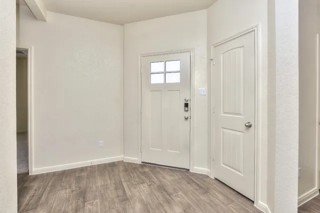 a view of an empty room with wooden floor and closet