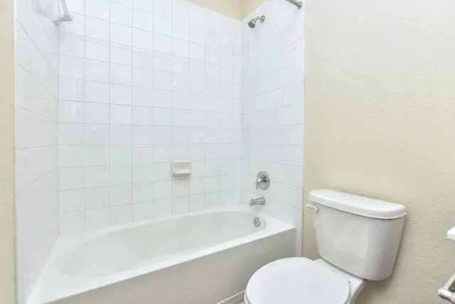 a white toilet sitting next to a bath tub