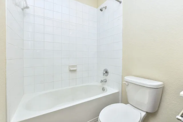 a white toilet sitting next to a bath tub
