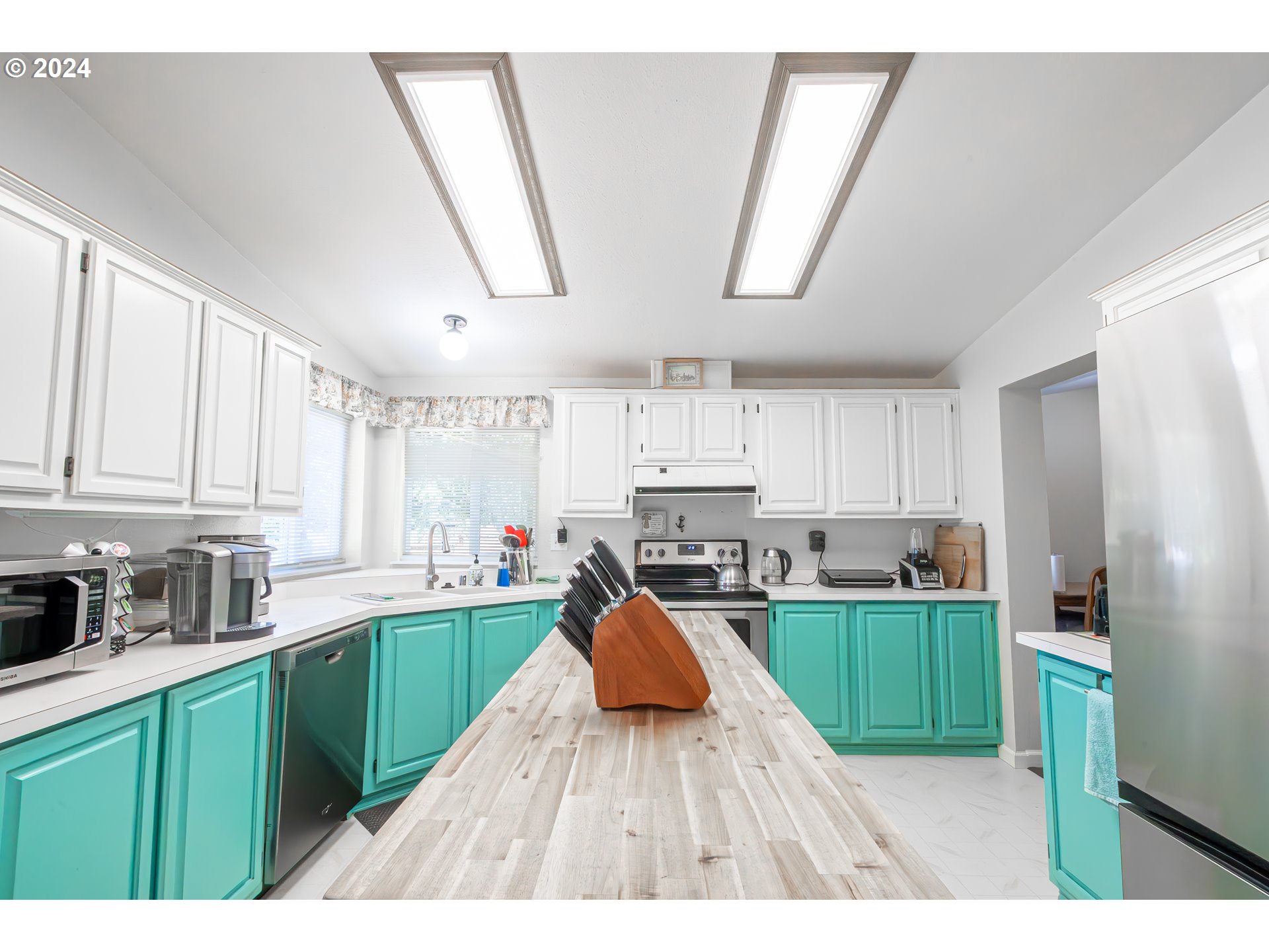 710 North Howe Street Carlton, OR 97111 - Photo 7 of 31 a kitchen with kitchen island white cabinets a refrigerator and a sink