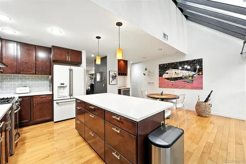 a living room with stainless steel appliances furniture a flat screen tv and kitchen view