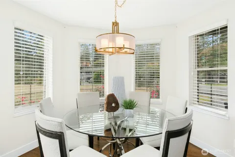 a kitchen with stainless steel appliances kitchen island granite countertop a table chairs and a refrigerator