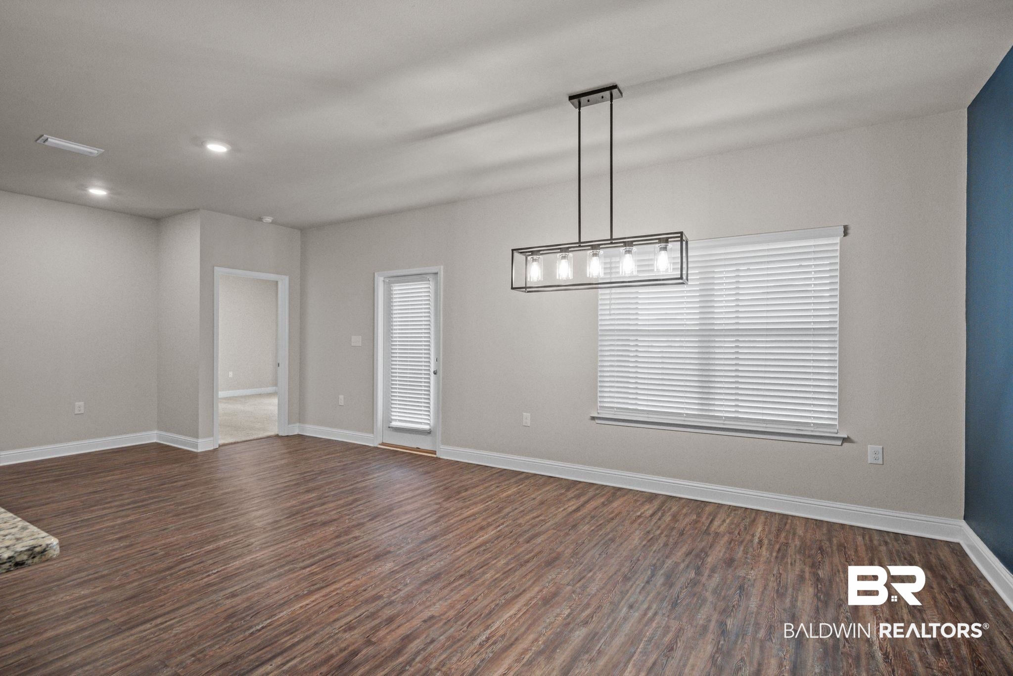 24769 Slater Mill Road Daphne, AL 36526 - Photo 17 of 38 Empty room featuring wood-type flooring and a chandelier