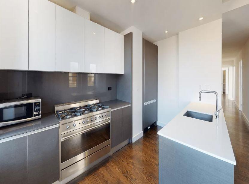 a kitchen with stainless steel appliances a stove a microwave and a hard wood floor