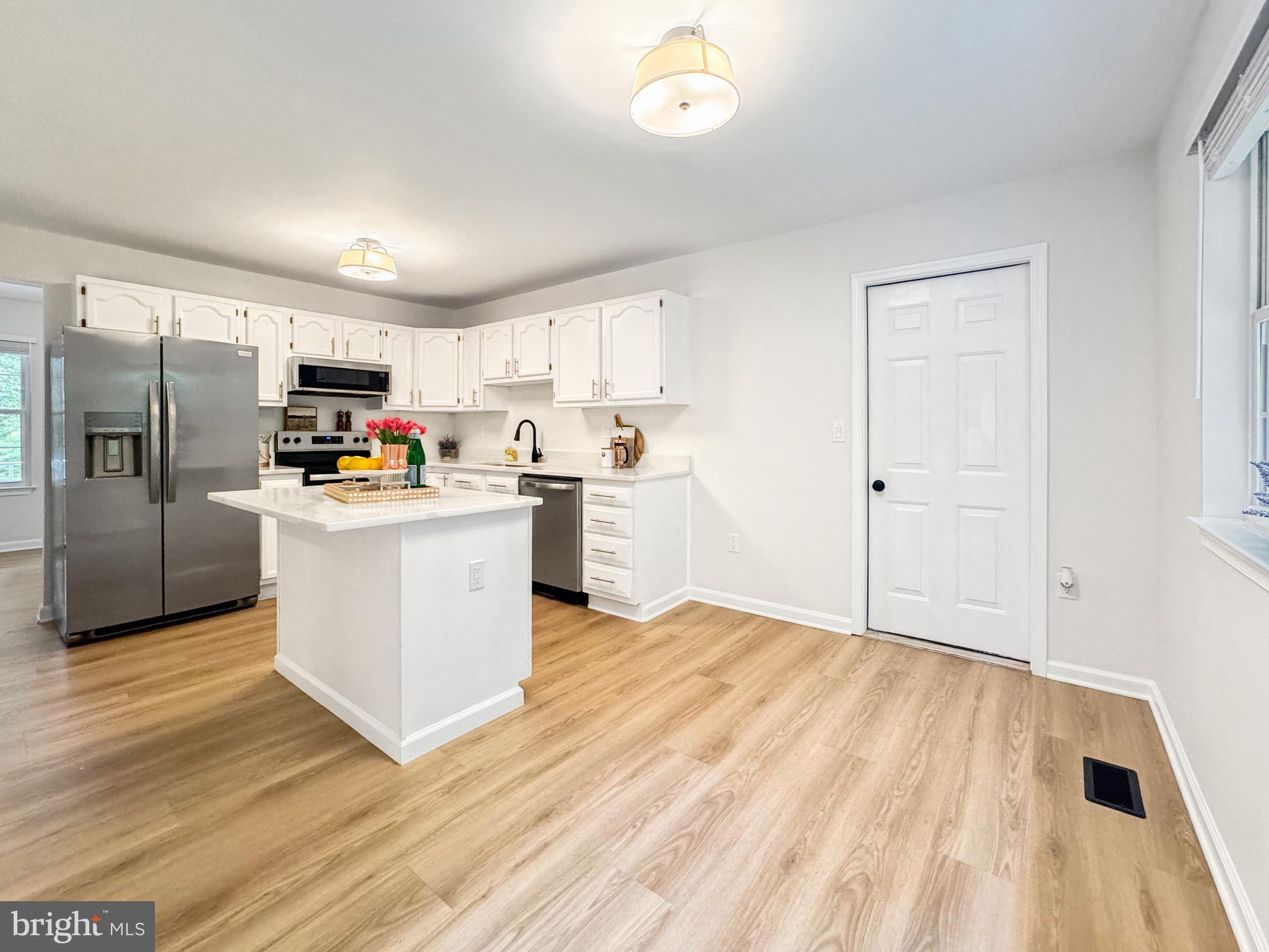 640 Santa Fe Trail Lusby, MD 20657 - Photo 13 of 32 a kitchen with stainless steel appliances a stove top oven a sink a refrigerator white cabinets and wooden floor