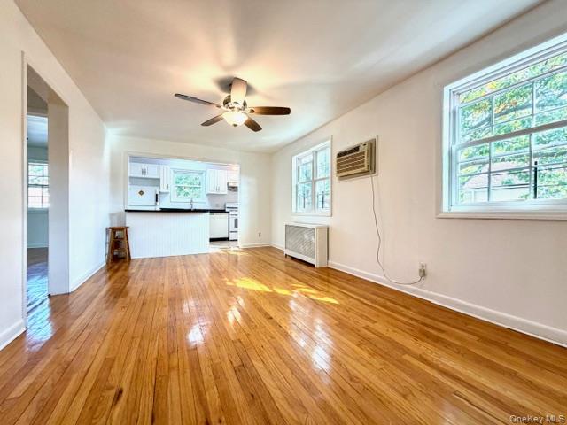 65-26B 223rd Place, Unit 2 Queens, NY 11364 - Photo 11 of 30 SUNNY- SE- living room with light wood finished floors, ceiling fan, radiator heating unit, and a wall mounted air conditioner