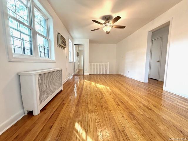 65-26B 223rd Place, Unit 2 Queens, NY 11364 - Photo 12 of 30 2 windows in LIVINGROOM with radiator heating unit, light wood-style flooring, and a ceiling fan