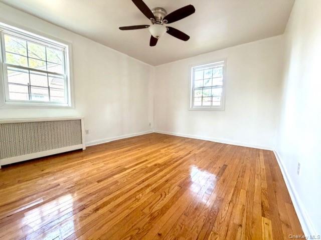 65-26B 223rd Place, Unit 2 Queens, NY 11364 - Photo 13 of 30 2 SIDES WINDOWS IN master bedroom with radiator, light wood-style flooring, and ceiling fan