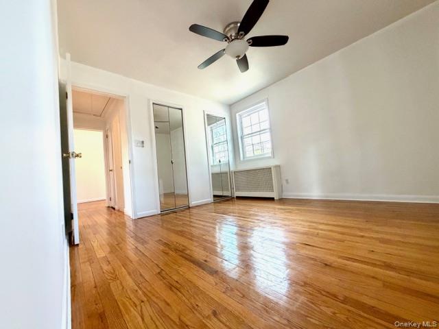 65-26B 223rd Place, Unit 2 Queens, NY 11364 - Photo 14 of 30 Master bedroom with light wood finished floors, attic access, radiator heating unit, ceiling fan, and two closets