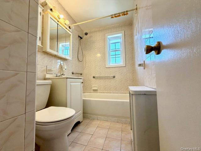 65-26B 223rd Place, Unit 2 Queens, NY 11364 - Photo 16 of 30 Full bath with tile walls, vanity, washtub / shower combination, and light tile patterned floors
