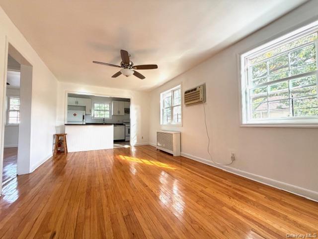 65-26B 223rd Place, Unit 2 Queens, NY 11364 - Photo 21 of 30 Unfurnished living room with light wood finished floors, radiator, a ceiling fan, and a wall mounted air conditioner
