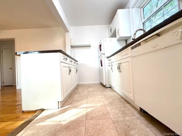 65-26B 223rd Place, Unit 2 Queens, NY 11364 - Photo 8 of 30 Kitchen featuring white appliances, dark countertops, white cabinets, and light tile patterned floors