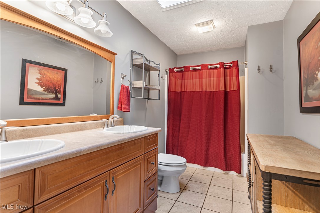 155 Ridgewood Boulevard Belpre, OH 45714 - Photo 36 of 49 Full bath featuring a textured ceiling, shower / bath combination with curtain, double vanity, and light tile patterned floors