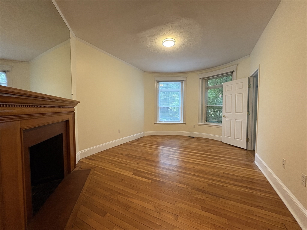 191 Winthrop Road, Unit 1 Brookline, MA 02445 - Photo 5 of 15 a view of an empty room with wooden floor and a window