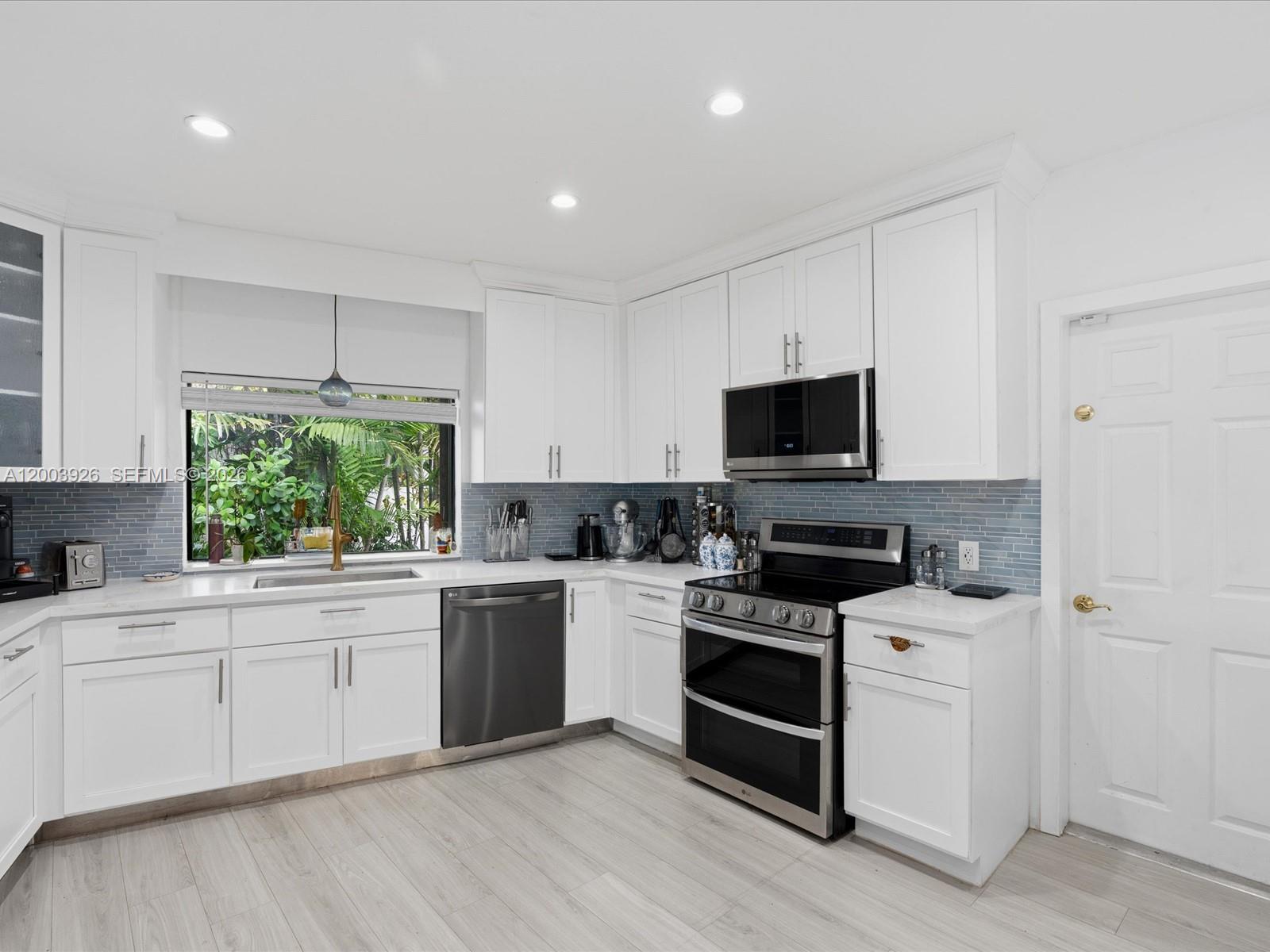 5000 Riviera Drive Coral Gables, FL 33146 - Photo 21 of 80 a kitchen with a sink stove and white cabinets