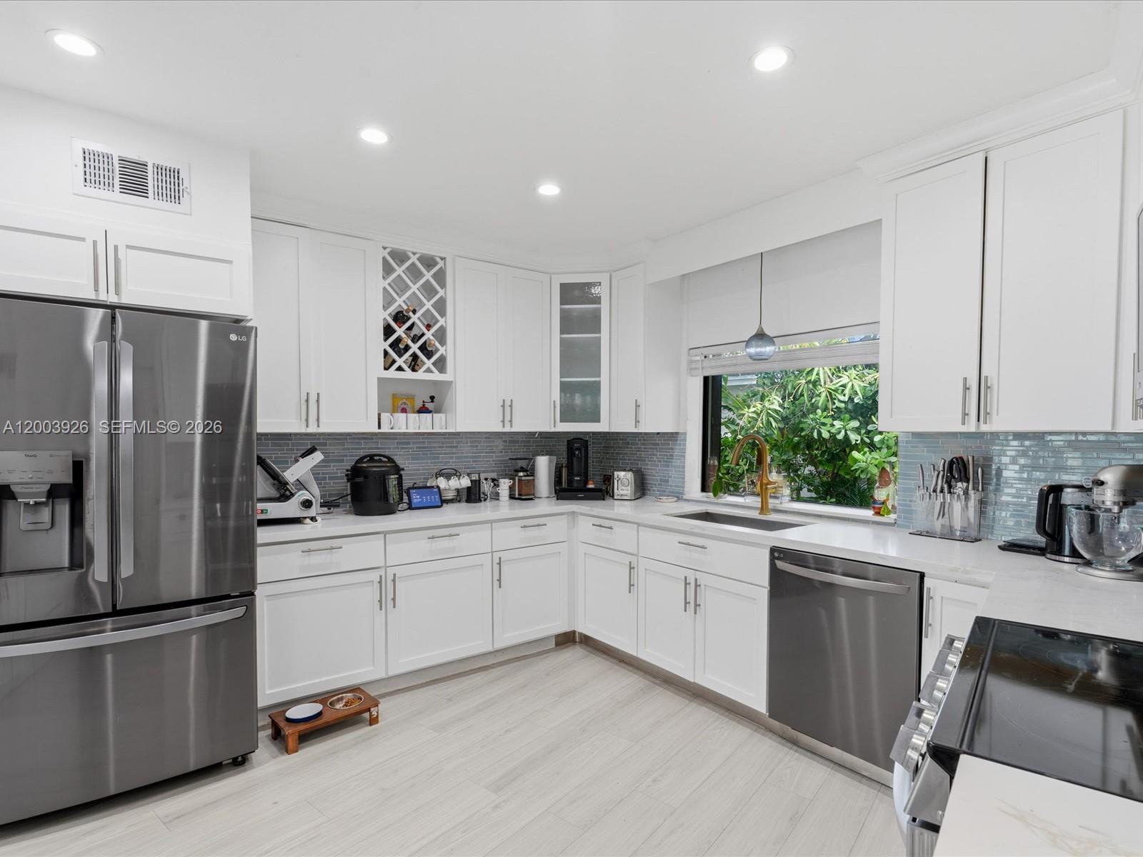5000 Riviera Drive Coral Gables, FL 33146 - Photo 22 of 80 a kitchen with white cabinets and stainless steel appliances