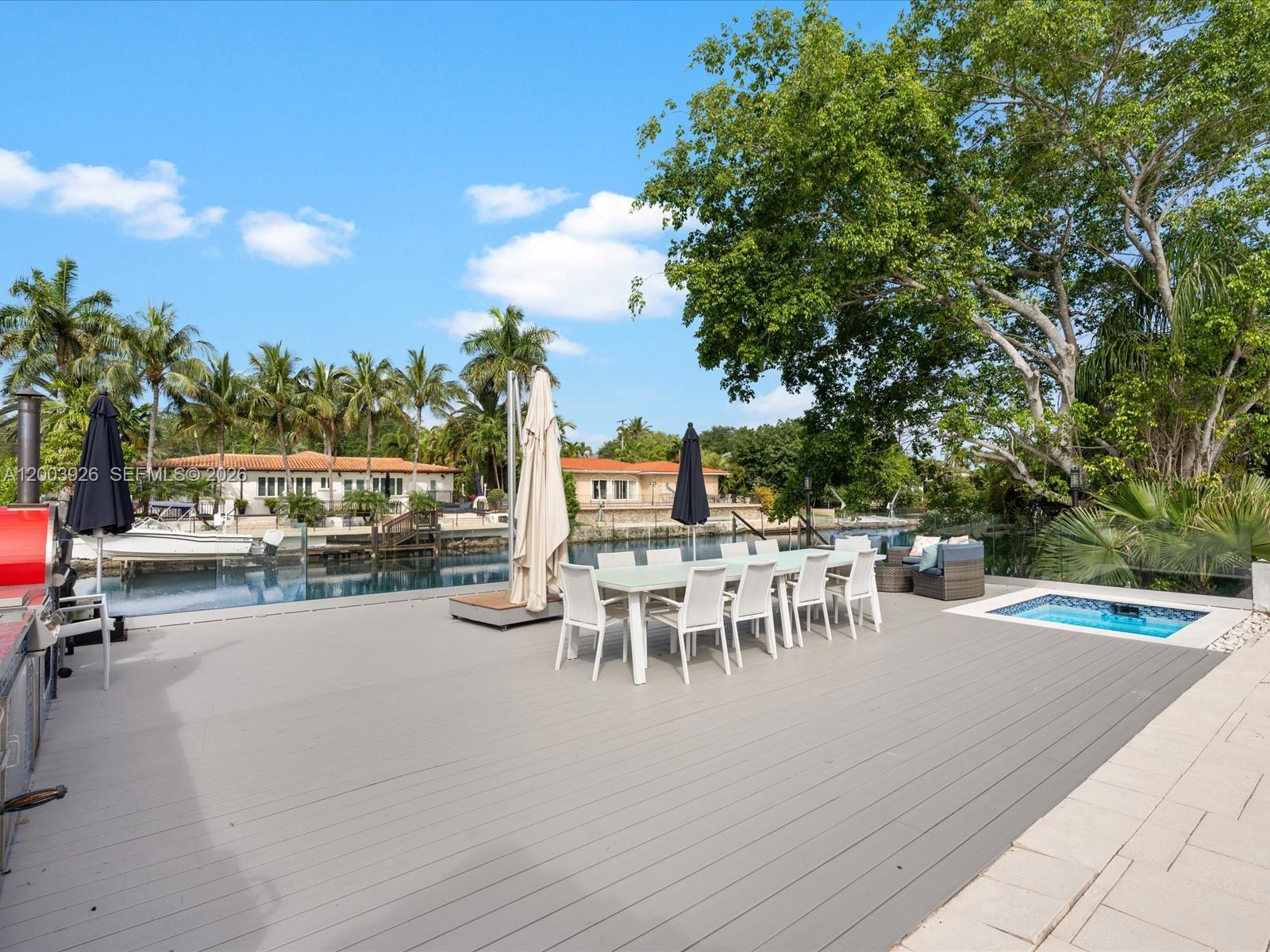 5000 Riviera Drive Coral Gables, FL 33146 - Photo 75 of 80 a view of a patio with dining table and chairs with potted plants and a large tree