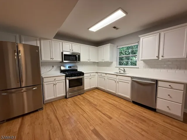 a kitchen with granite countertop a refrigerator stove top oven and sink