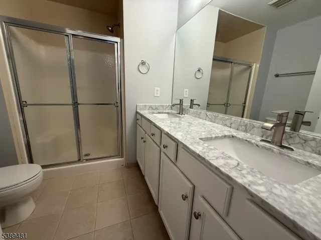 a bathroom with a granite countertop sink a toilet and a shower