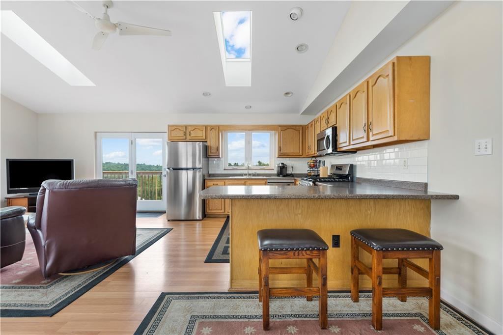 321 Chambers Ridge Road West Alexander, PA 15376 - Photo 16 of 42 a kitchen with stainless steel appliances granite countertop a stove top oven a sink a dining table and chairs with wooden floor