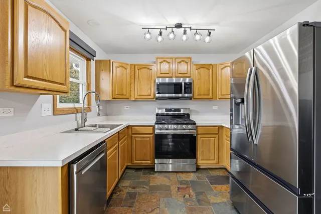 a kitchen with stainless steel appliances granite countertop a refrigerator a stove a sink and a microwave