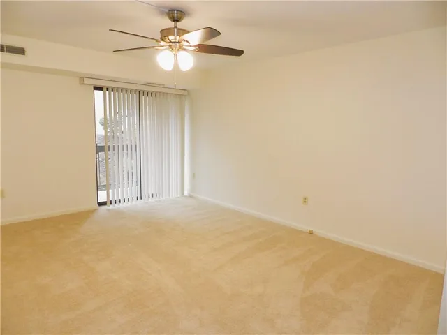 an empty room with a chandelier fan and windows