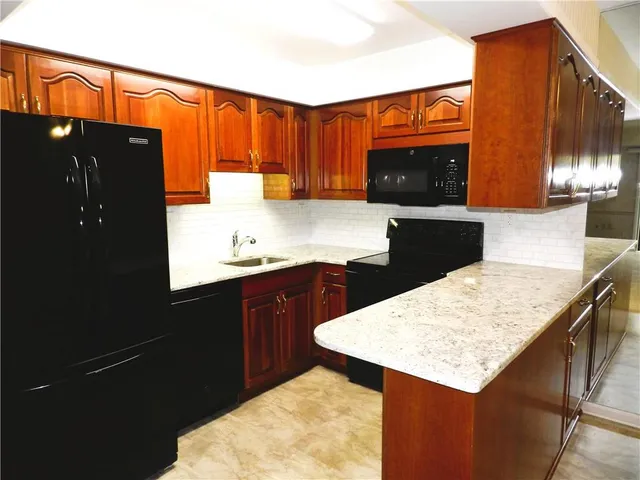 a kitchen with a sink a refrigerator and wooden cabinets
