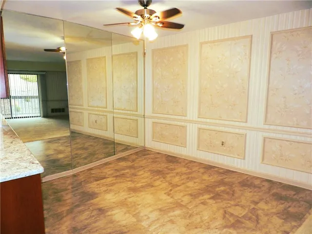 a view of an empty room with cabinet and chandelier fan