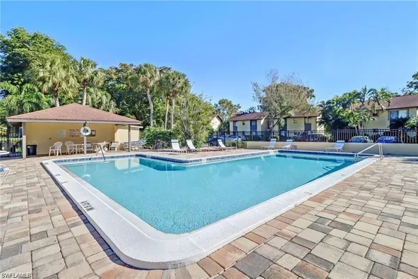 a view of a swimming pool with lawn chairs under an umbrella