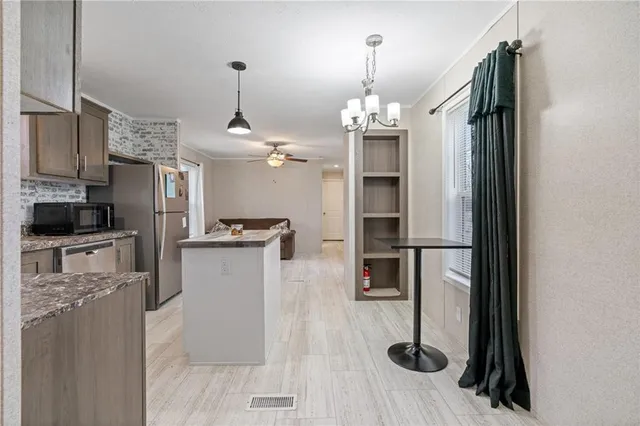 a kitchen with stainless steel appliances granite countertop a refrigerator a oven a sink dishwasher and white cabinets with wooden floor