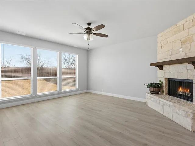 a view of an empty room with wooden floor fireplace and a window
