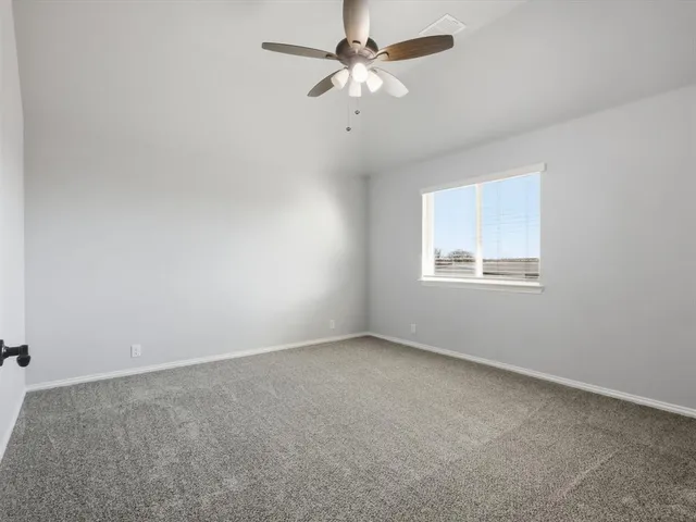 an empty room with a window and a ceiling fan
