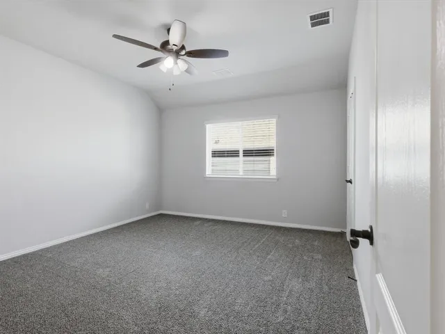 an empty room with a ceiling fan and window