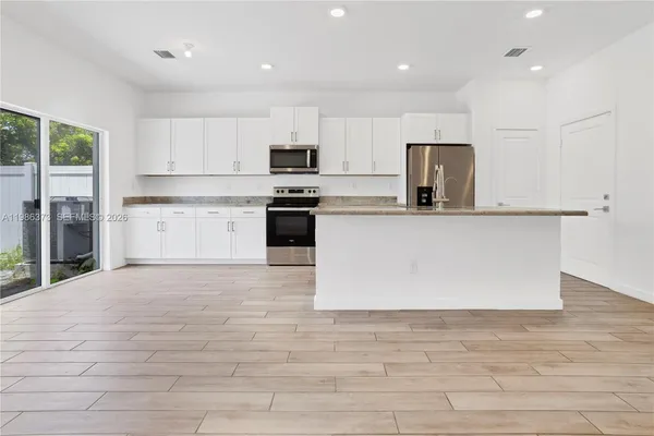 a large kitchen with stainless steel appliances a refrigerator a stove top oven a sink and dishwasher