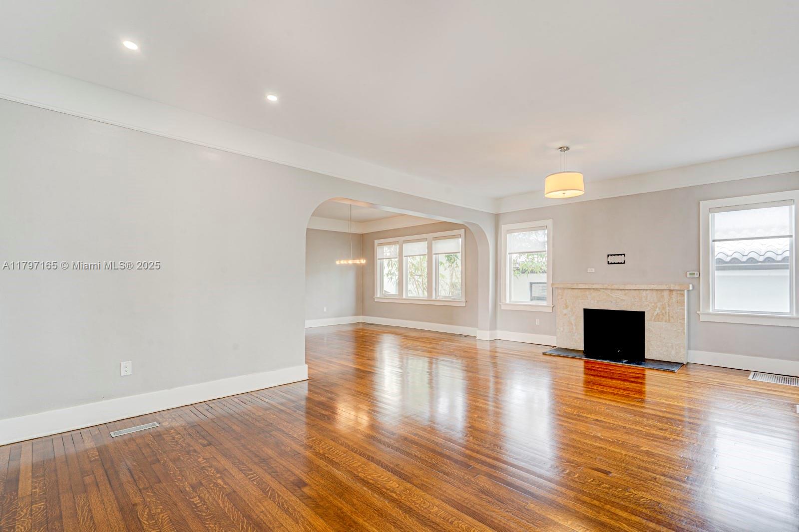428 Southwest 23rd Road Miami, FL 33129 - Photo 4 of 36 an empty room with wooden floor fireplace and windows