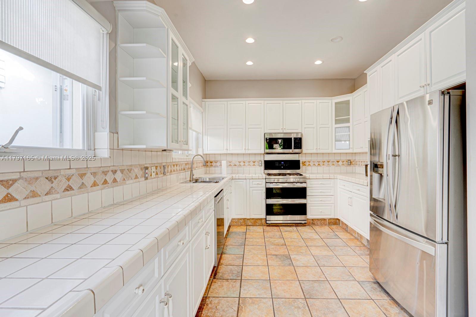 428 Southwest 23rd Road Miami, FL 33129 - Photo 10 of 36 a kitchen with granite countertop a refrigerator and a stove top oven