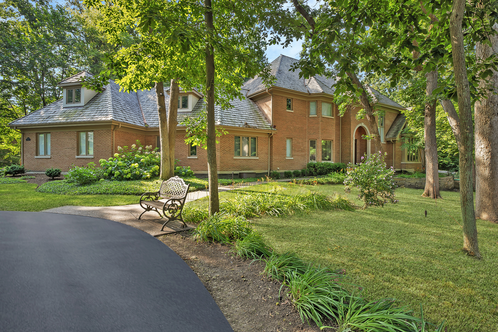 a view of a brick house with a big yard and large trees