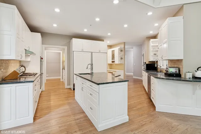 a large kitchen with stainless steel appliances kitchen island granite countertop a large counter top and a stove top oven