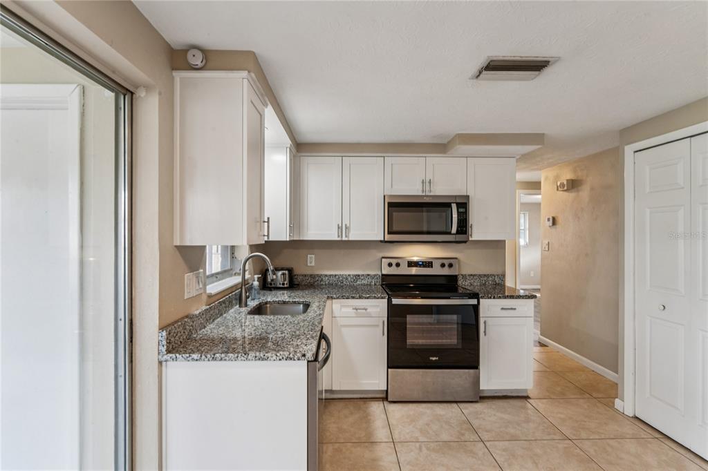 4837 Vision Avenue Holiday, FL 34690 - Photo 14 of 38 a kitchen with stainless steel appliances granite countertop a stove top oven a sink and a granite counter tops