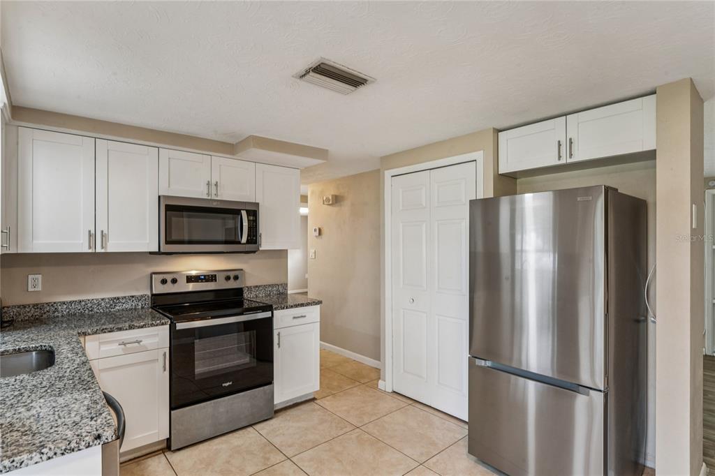 4837 Vision Avenue Holiday, FL 34690 - Photo 15 of 38 a kitchen with stainless steel appliances granite countertop a refrigerator stove and microwave
