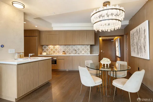 a large white kitchen with granite countertop a sink and dishwasher a stove top oven with wooden floor